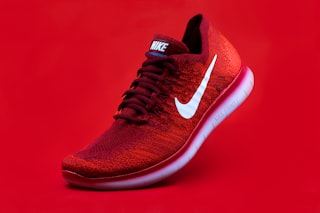 Red knit running shoe on a vivid red studio background